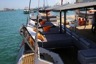 Cubierta del catamarán con cojines grises y naranjas, amarrado en el puerto