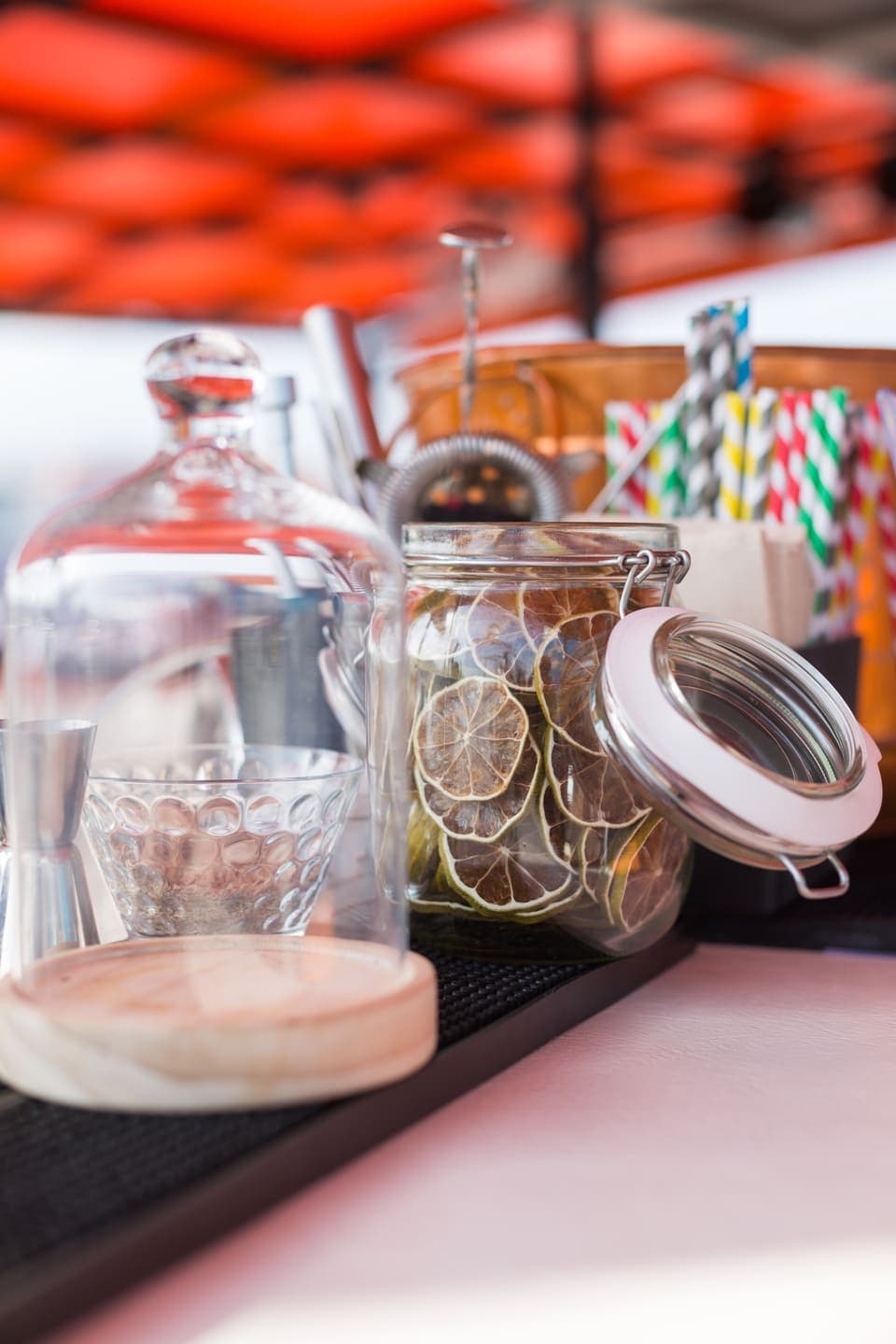 Detalle de barra a bordo con tarro de rodajas de cítricos secos y pajitas de colores