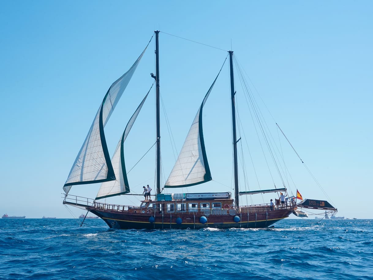 Velero de dos palos con las velas desplegadas navegando en el mar