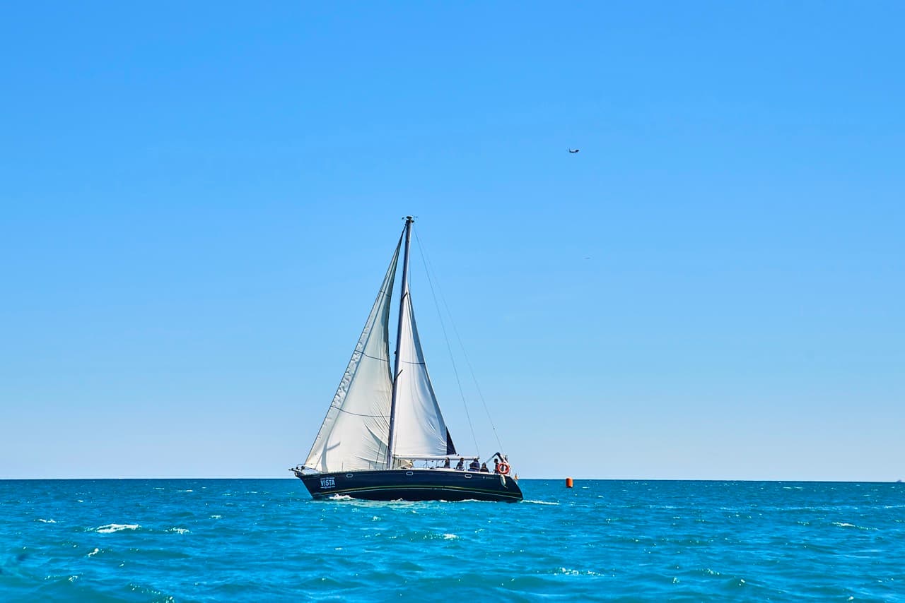 Velero navegando en solitario sobre el mar bajo un cielo despejado