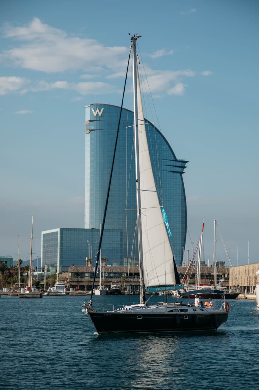 Velero navegando frente al Hotel W de Barcelona con la vela izada