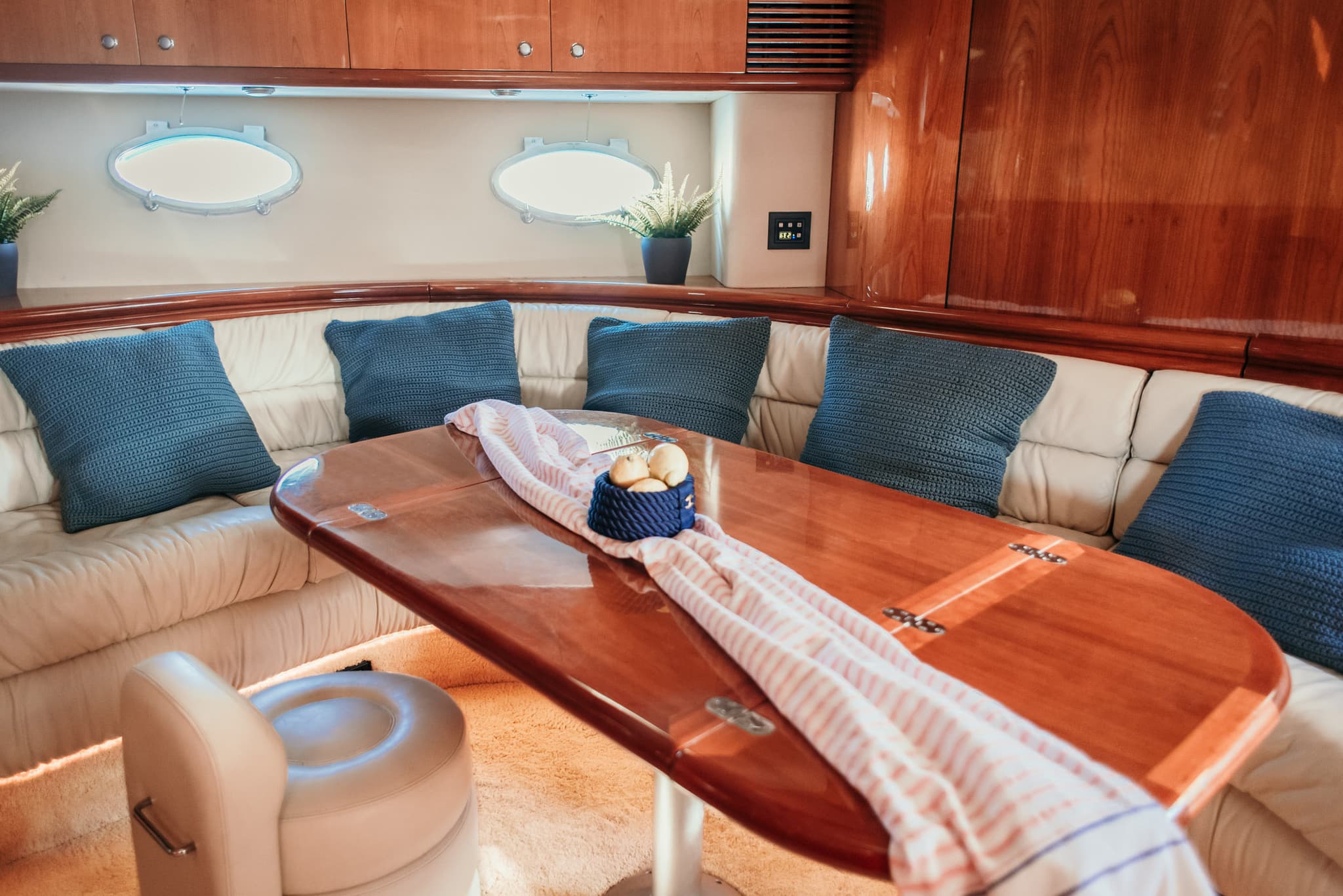Salón interior del yate con mesa de comedor de madera y asientos de cuero color crema