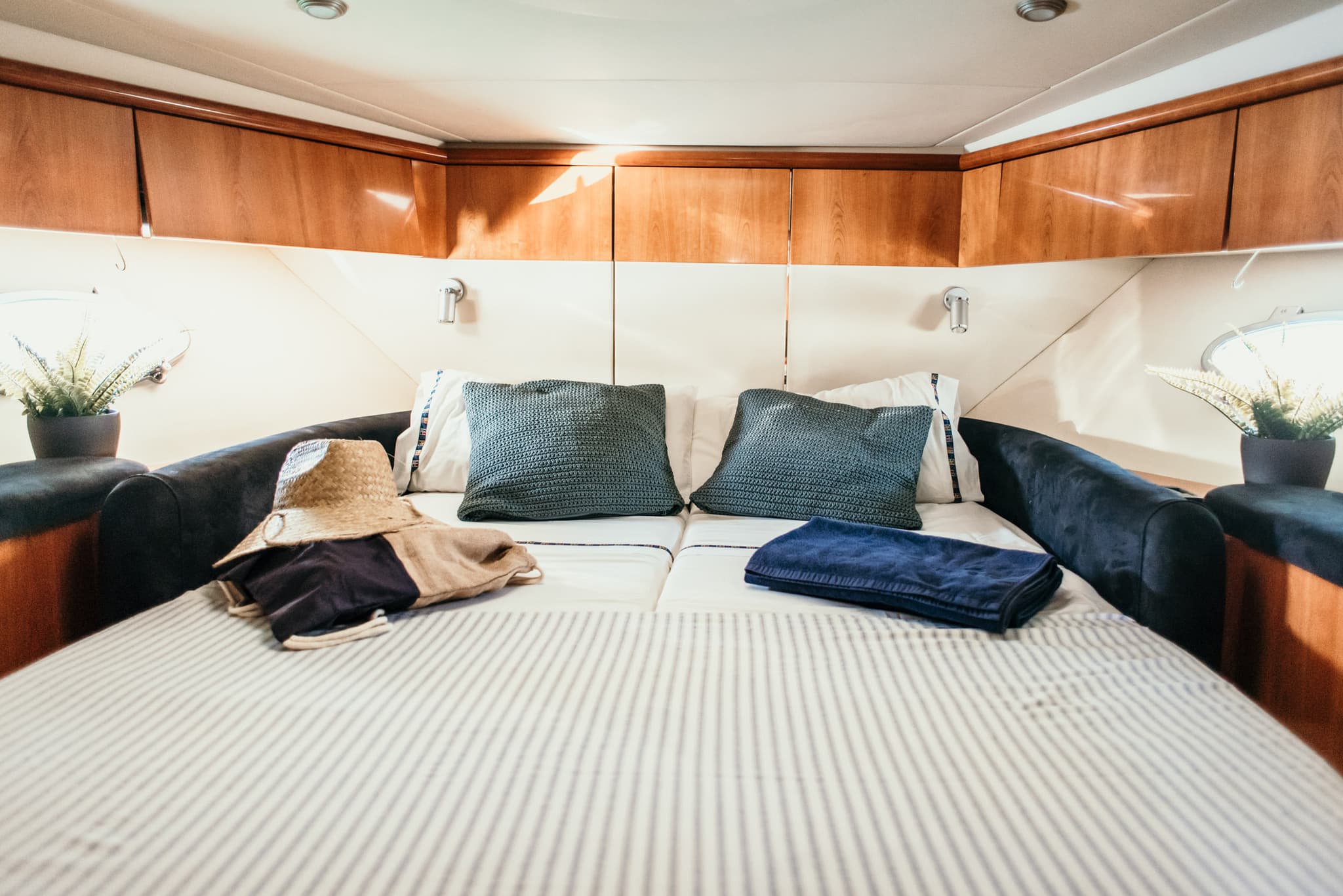 Camarote del yate con la cama hecha, un sombrero de paja y toallas dobladas
