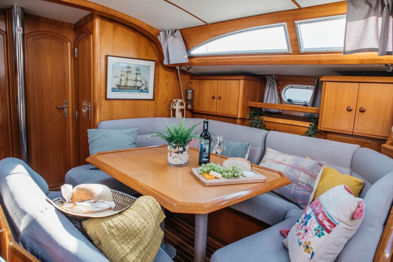 Salón de un velero con vino y una tabla de quesos sobre la mesa de comedor
