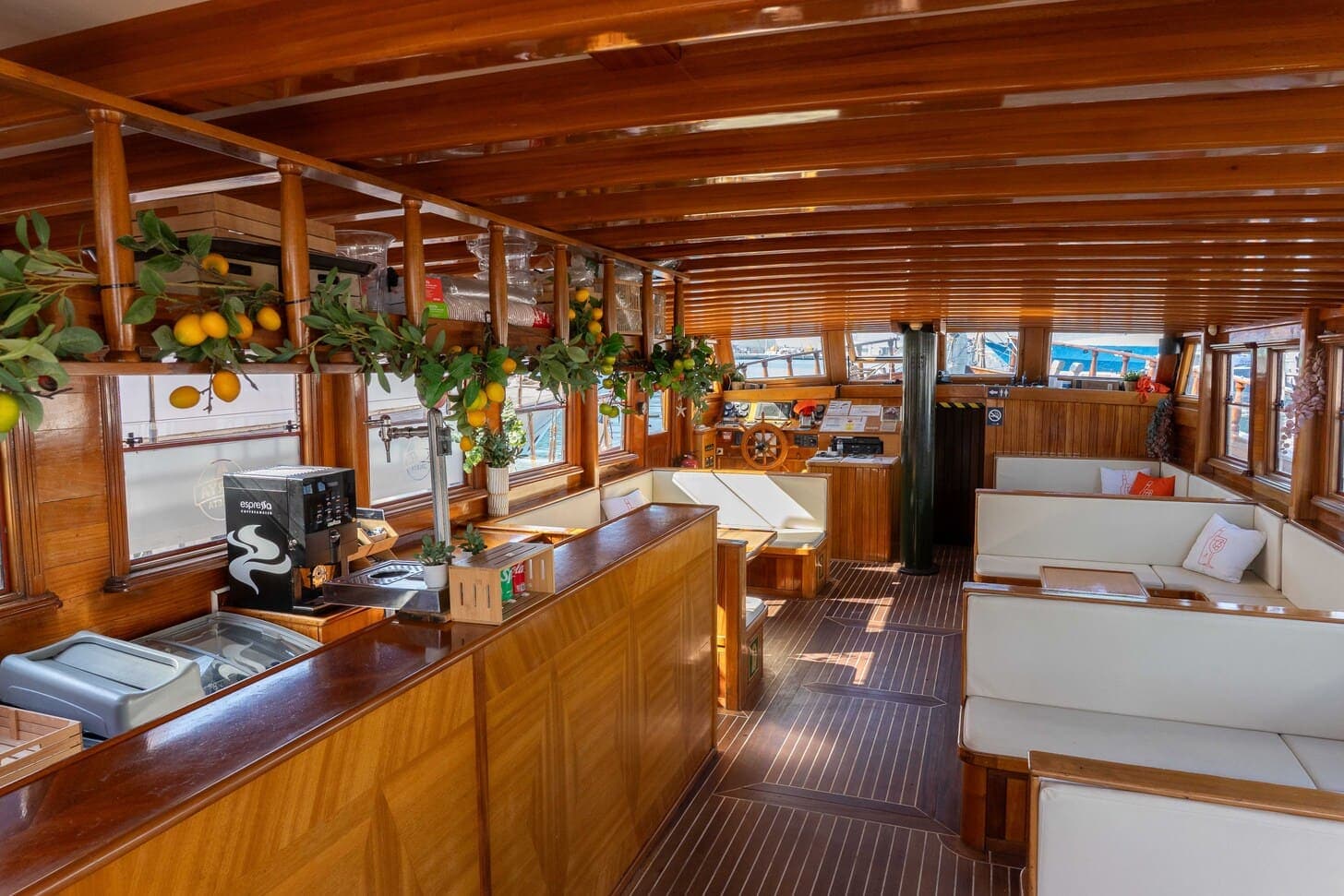 Barra de madera con cafetera espresso en el salón interior de un velero decorado con cítricos