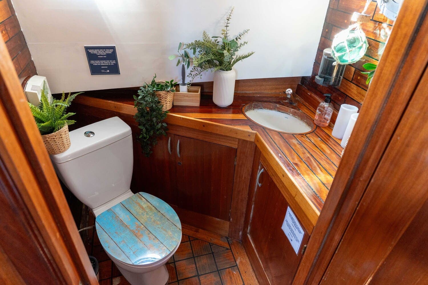 Aseo de madera a bordo de un velero con plantas decorativas junto al lavabo