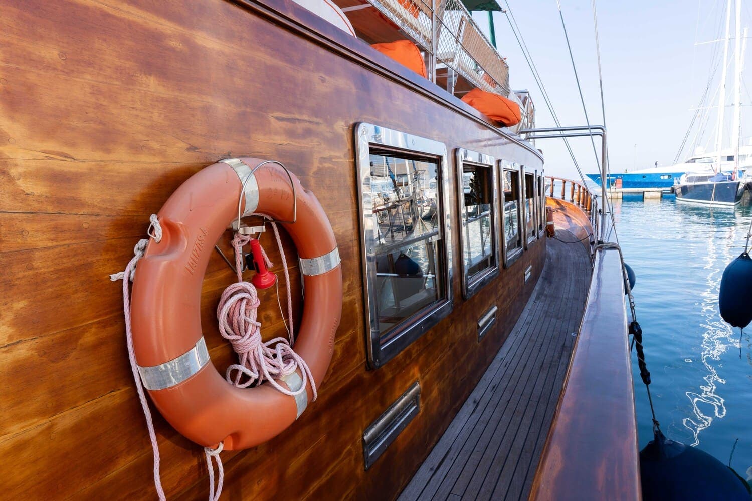 Casco de madera de un velero con un salvavidas naranja colgado junto a las ventanas de la cabina