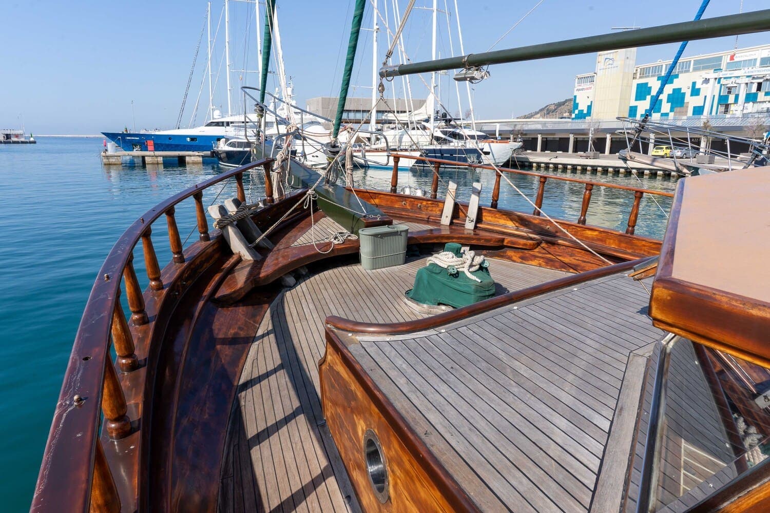Proa de madera de un velero amarrado en el puerto con un cabo de amarre enfundado en verde