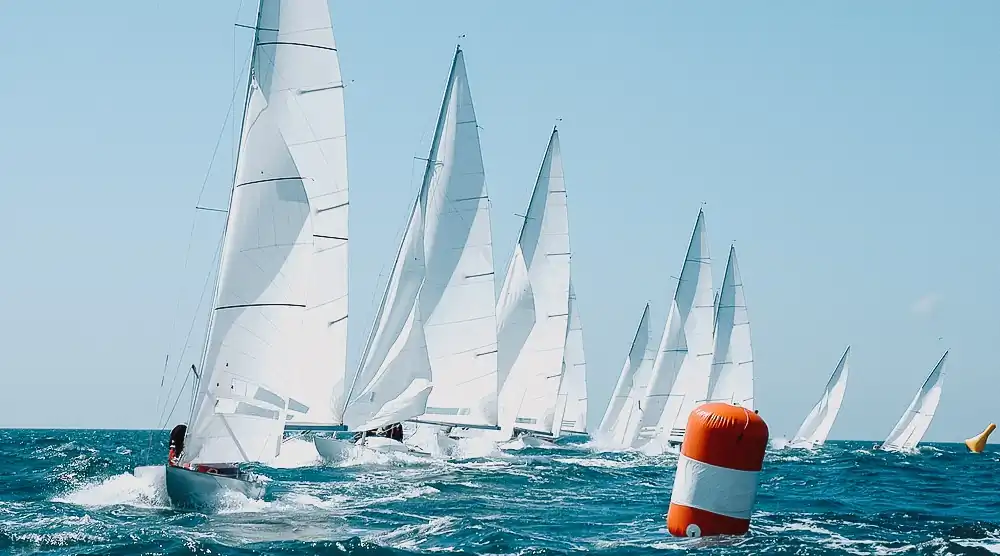 Flota de veleros compitiendo junto a una boya de regata en el mar
