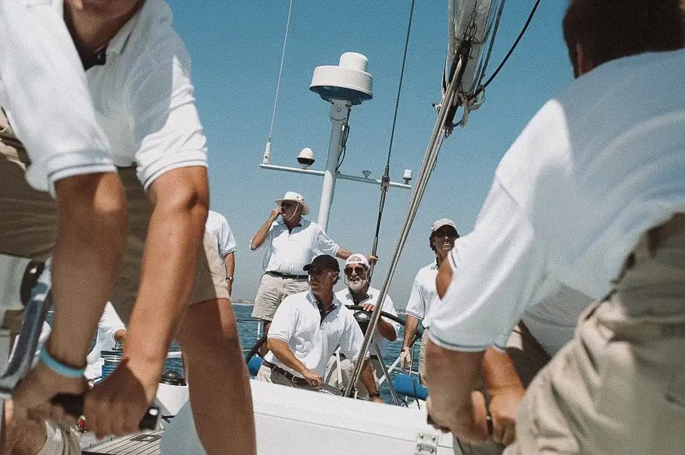 Tripulación con polo blanco maniobrando las escotas a bordo durante la regata corporativa