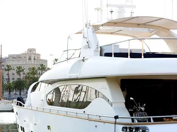 Yate a motor Maiora atracado en puerto con edificios y palmeras al fondo