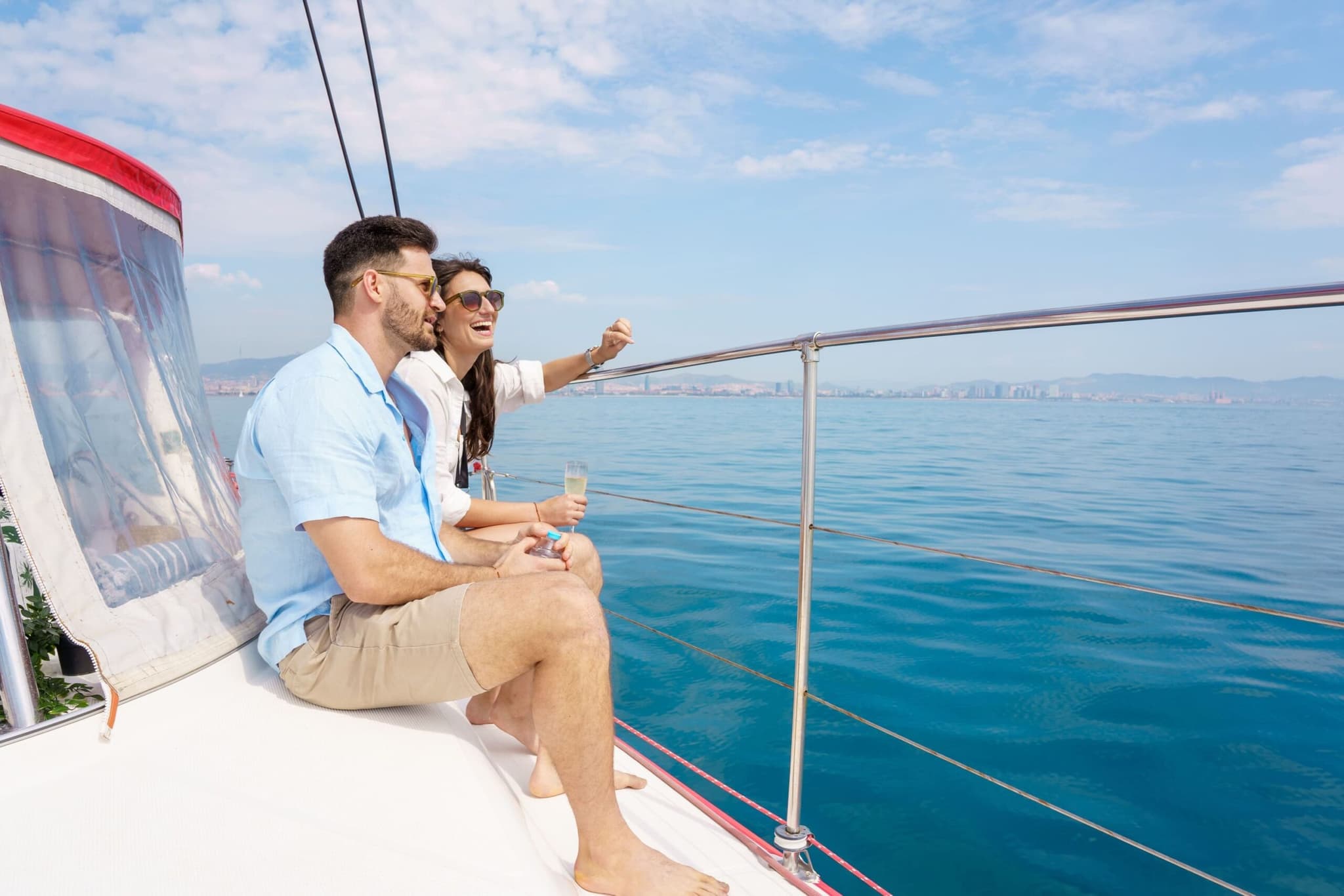 Pareja sentada en la proa del catamarán señalando el skyline de Barcelona