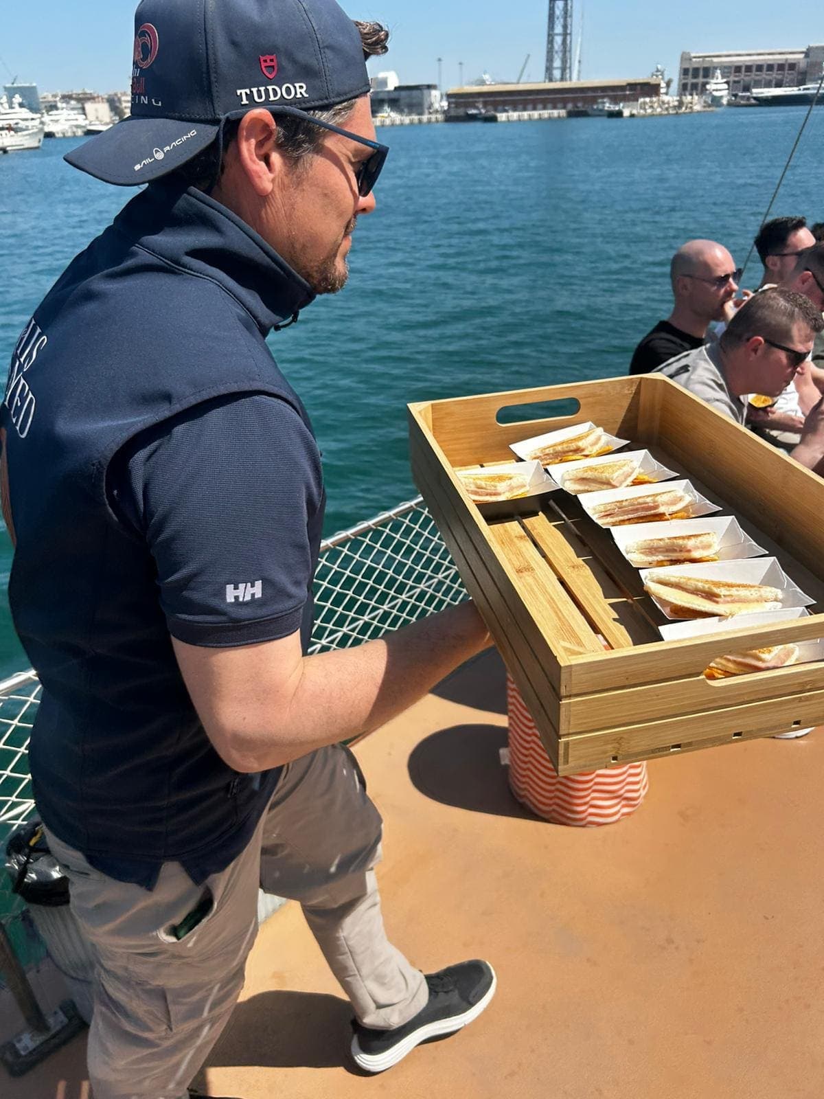 Camarero sirviendo bandeja con porciones individuales de bocadillo en la cubierta del barco