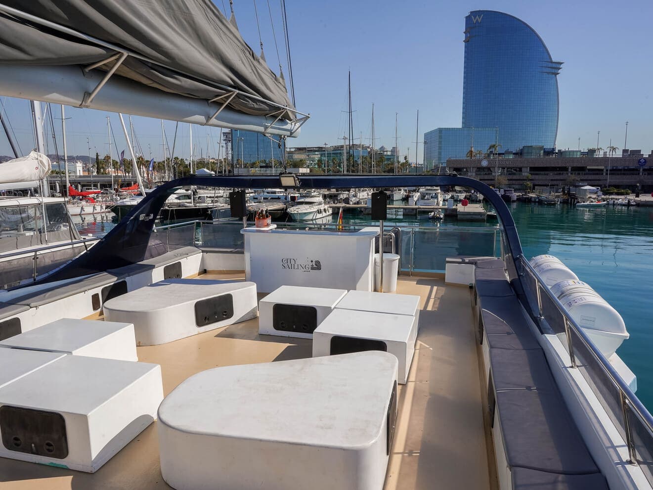 Barra de bar en la cubierta de un catamarán con vistas al hotel W de Barcelona