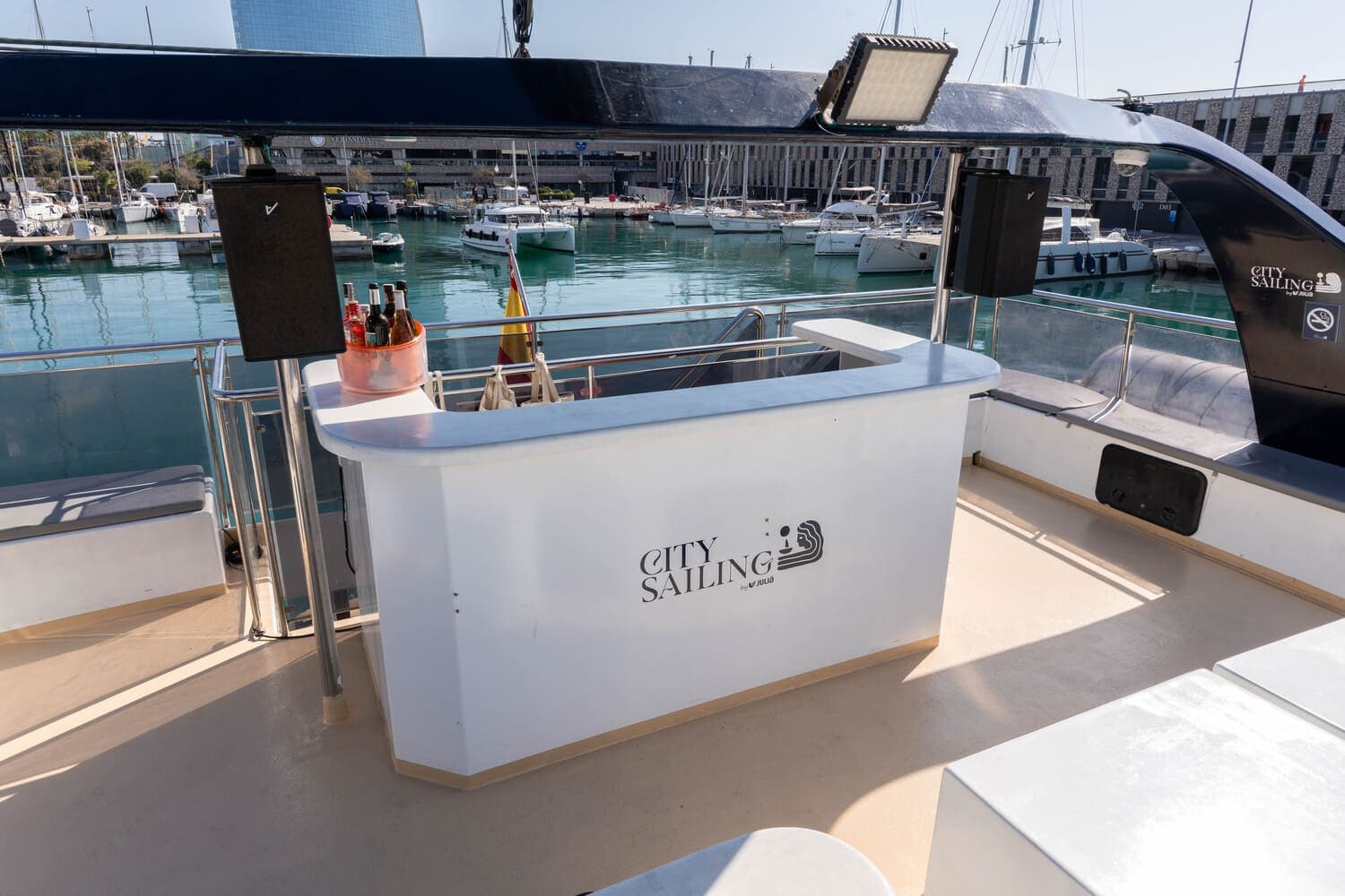 Barra con bebidas y cubo de hielo en la cubierta de un catamarán, con el hotel W al fondo