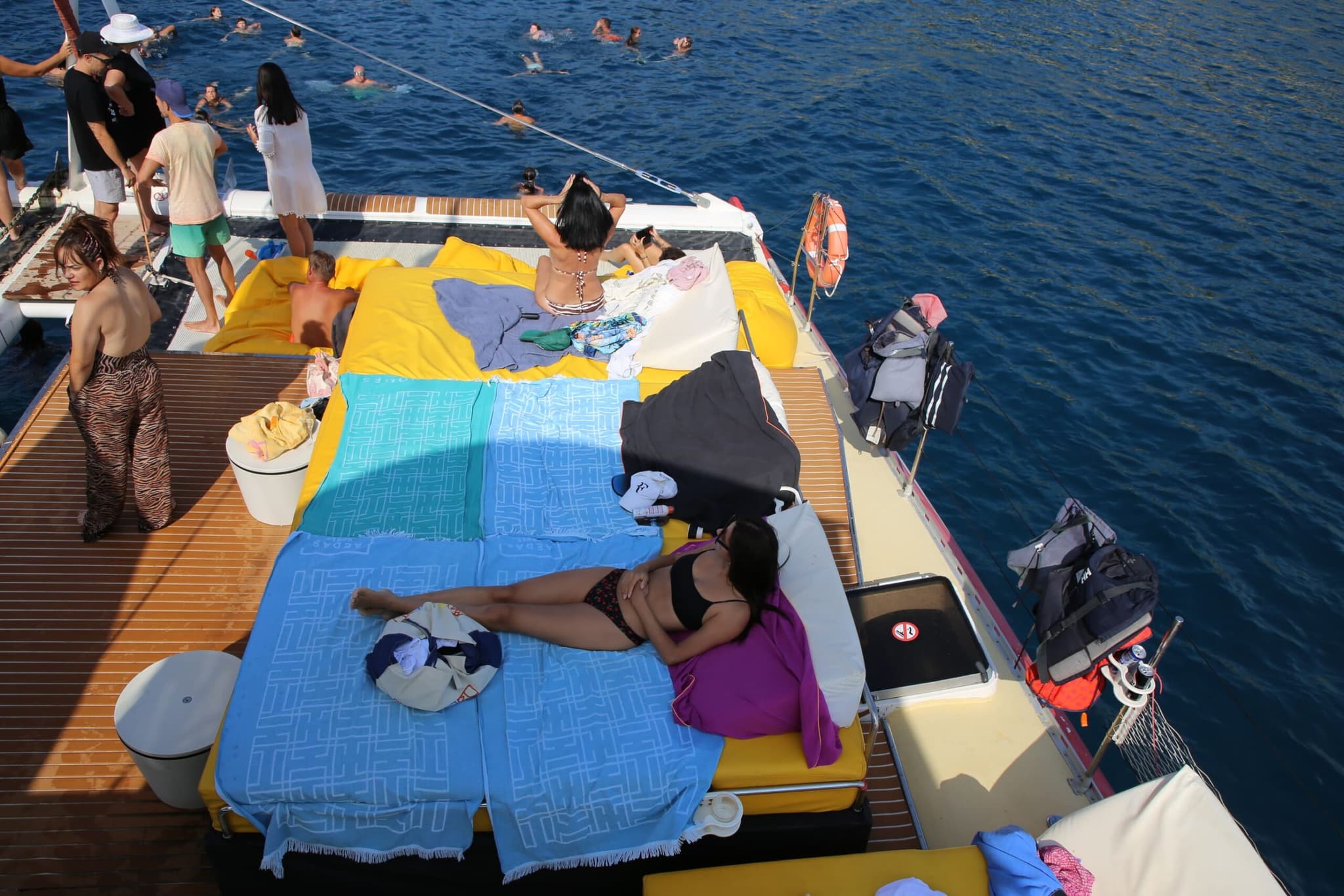 Vista aérea de la cubierta con bañistas nadando junto al catamarán en el mar