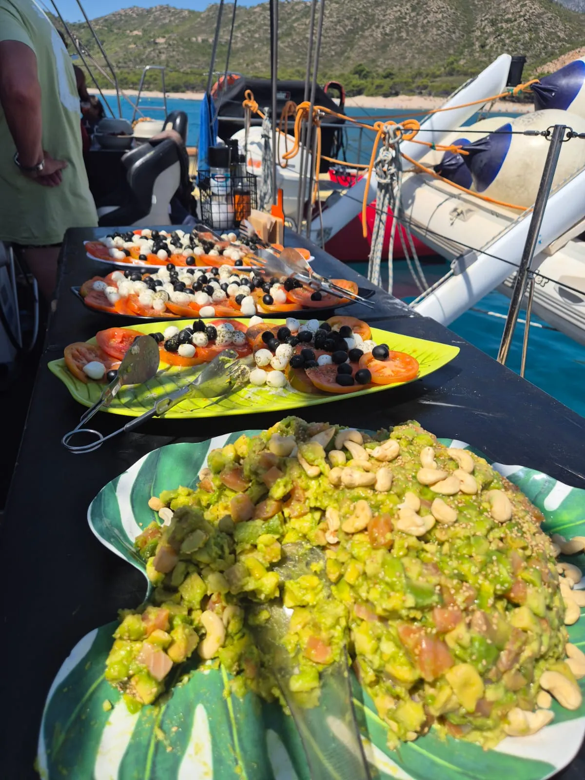 Ensaladas de tomate, mozzarella y aguacate servidas en la mesa del catamarán junto a la costa