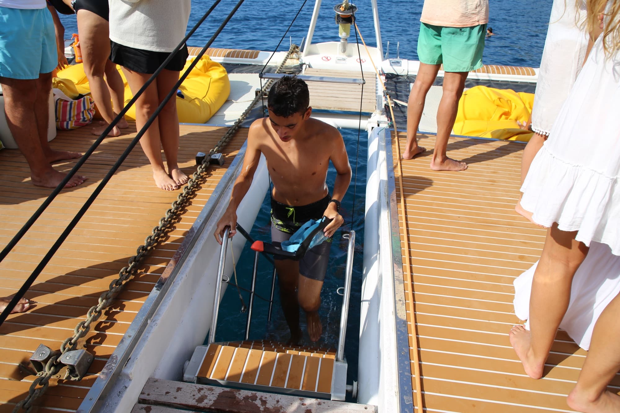 Chico bajando la escalerilla de baño con aletas de snorkel en la mano