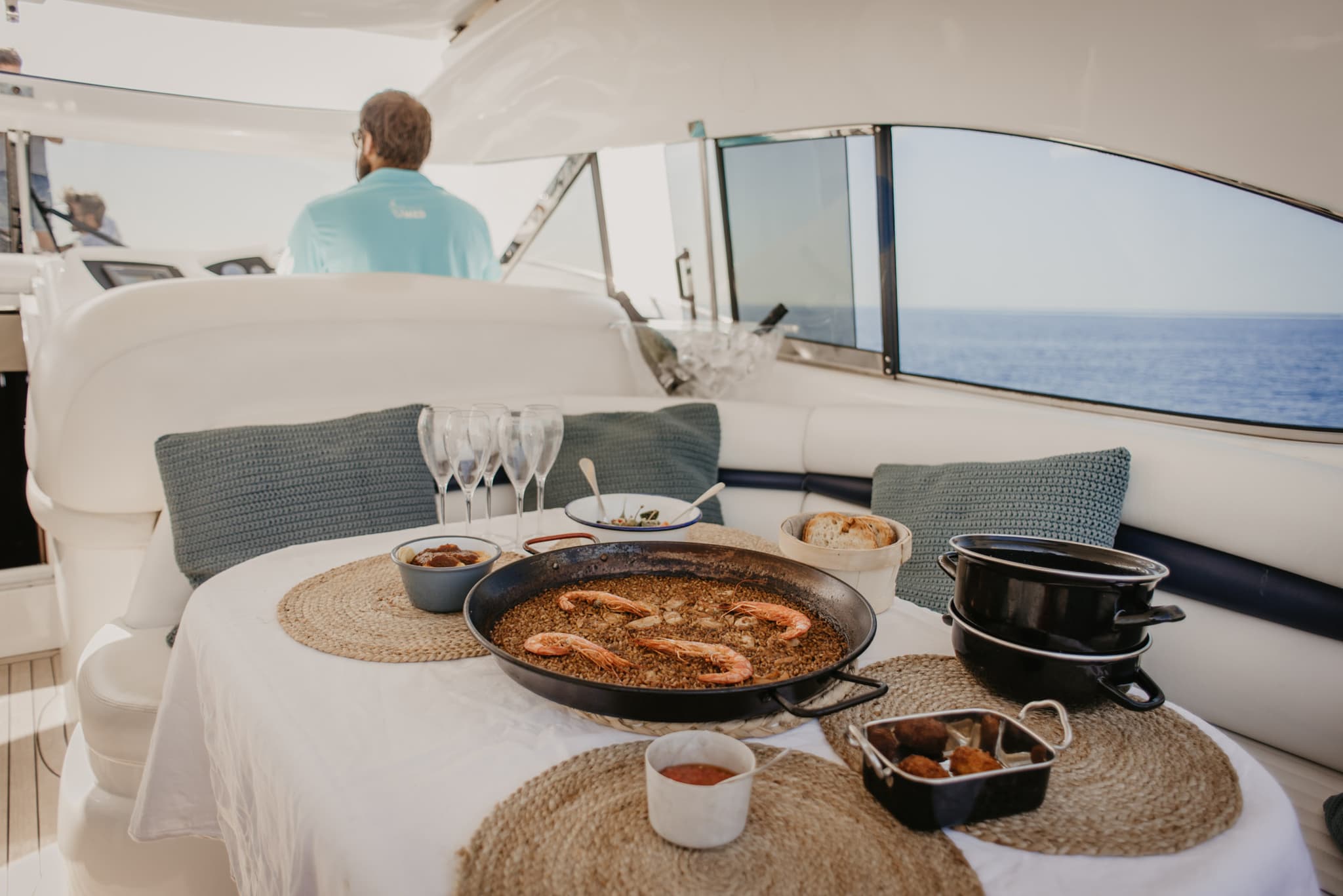 Mesa con paella y tapas servida en la cubierta trasera del yate con vistas al mar