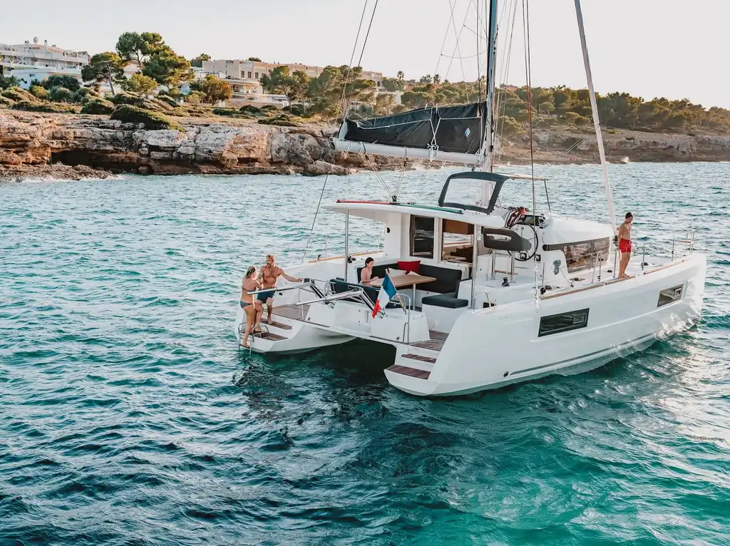 Catamarán Lagoon 40 fondeado junto a una cala con bañistas en la popa