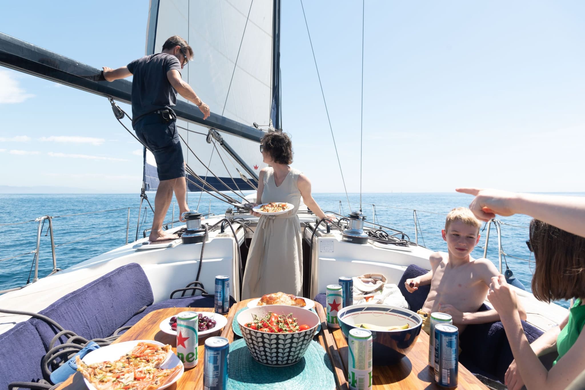 Familia disfrutando de un almuerzo a bordo de un velero con pizza y bebidas